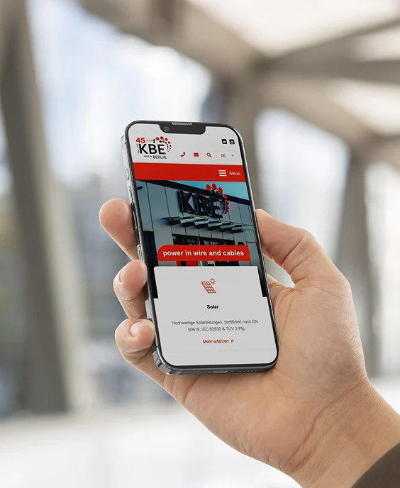 Mockup Darstellung von unserem Relaunch Projekt KBE Elektrotechnik. Hand hält Telefon.